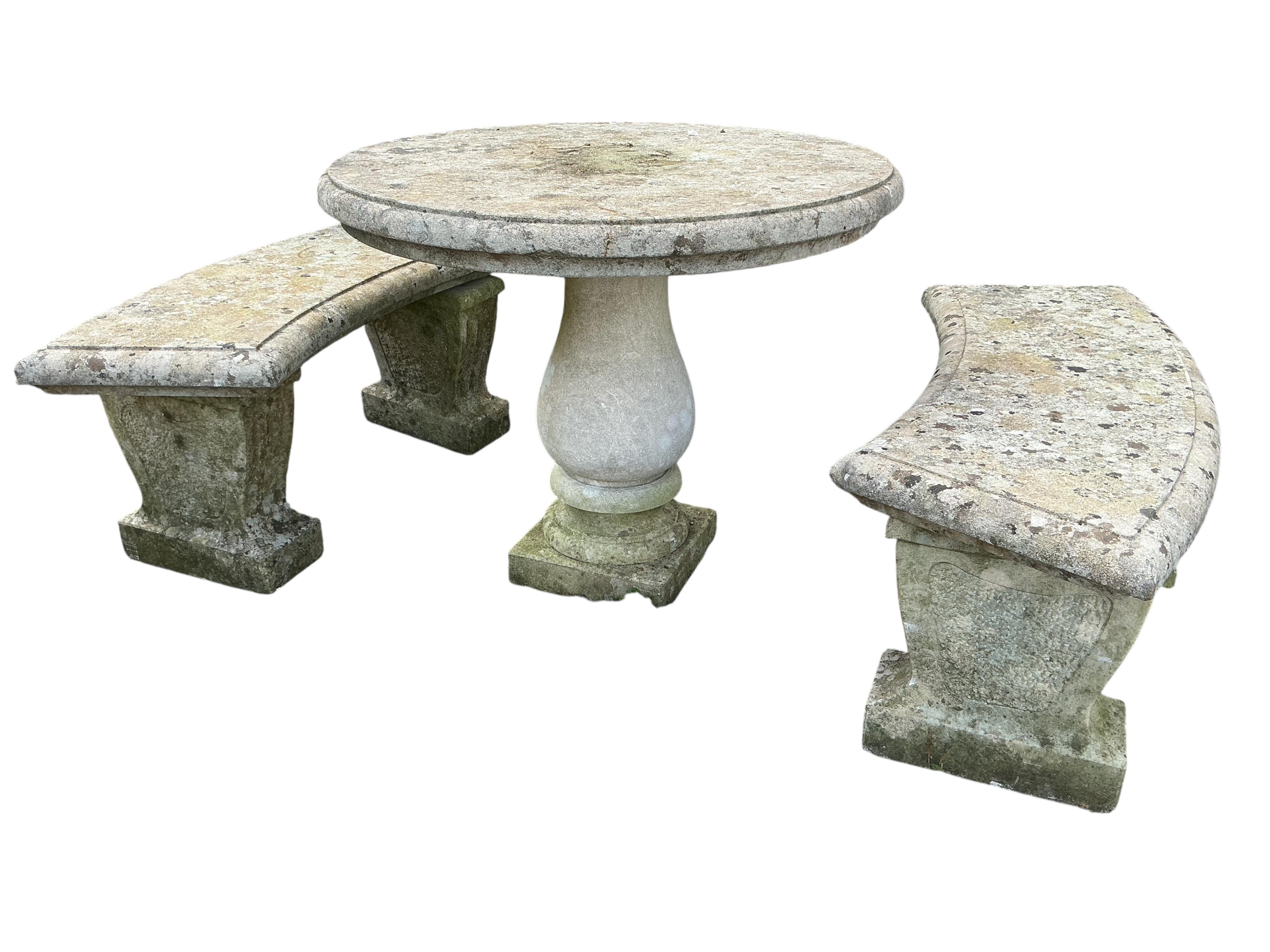 A circular reconstituted stone garden table, diameter 74cm, height 90cm, and two curved benches